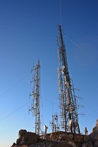 Low angle view of electricity pylon against clear blue sky