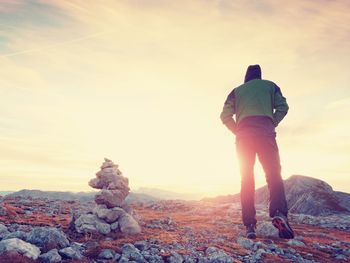 Tourist guide at stocked stones on alps peak. strong hiker enjoy sunset in high mountains. long trek