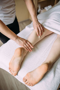 The masseur gives a massage to the female feet at the spa.