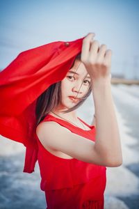 A beautiful woman in a long red dress stands tall among salt fields and blue skies.
