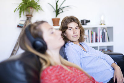 Portrait of woman sitting with female friend on sofa at home