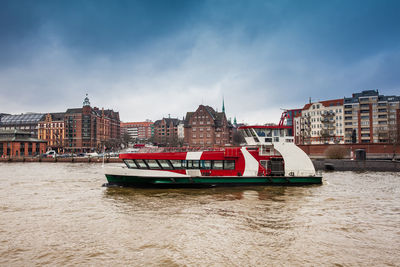 Boat in river by city against sky