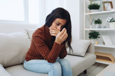 Young woman using phone while sitting on sofa at home