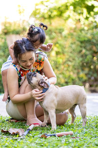 Mother and daughter playing with dog at backyard