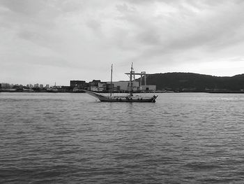 Boats in sea against cloudy sky