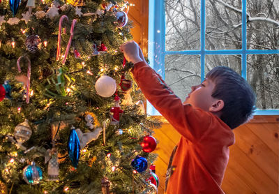 Little boy decorates a festive christmas tree at home