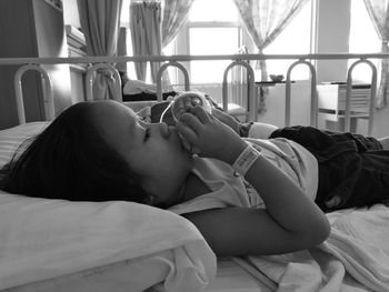 Close-up of girl eating fruit while lying on bed in hospital