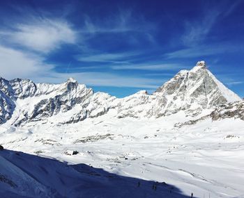 Scenic view of snowcapped mountains against blue sky