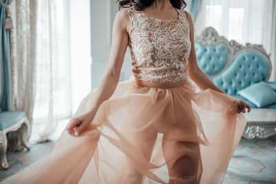 Midsection of woman wearing bridal dress standing at home
