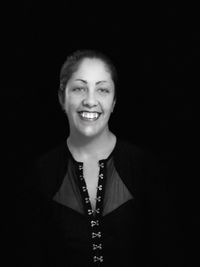 Portrait of a smiling young woman over black background