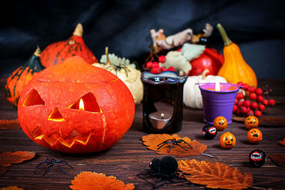 Halloween pumpkins on a wooden dark table with spiders, candles, pumpkins, leaves. 