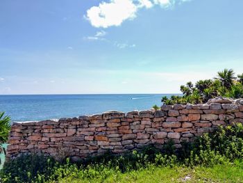 Stone wall by sea against sky