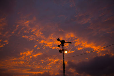 Low angle view of silhouette birds perching on orange sky