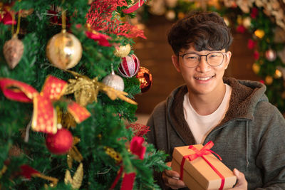 Portrait of smiling man holding gift box at home