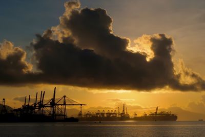 Commercial dock by sea against sky during sunrise 