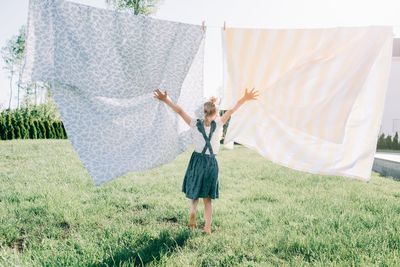 Young girl dancing through the washing on the line in the yard