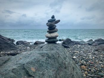 Stack of pebbles on beach against sky