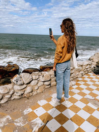 Rear view of young woman standing at beach