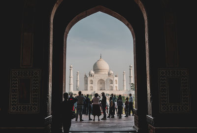 People seen through arch standing in front of taj mahal