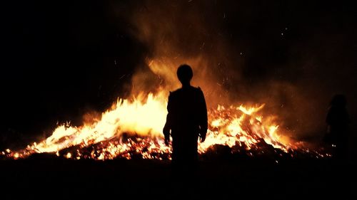 Silhouette man standing against bonfire