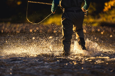 Fly-fisherman wading through river in late evening light