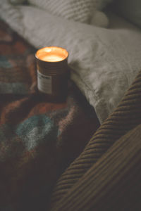 High angle view of lit tea light on bed