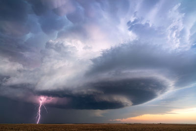 Supercell thunderstorm with lightning bolt over a field near sublette, kansas.