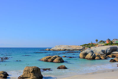 Rocks on beach against clear blue sky