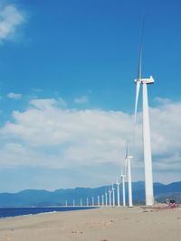 Wind turbines on beach against sky