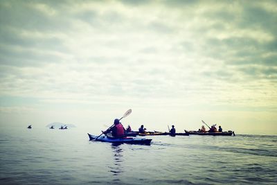 Boats in sea against cloudy sky