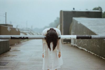 Woman bending over barricade outdoors