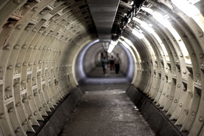 People walking through illuminated tunnel