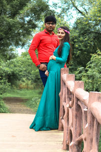 Portrait of pregnant young woman standing with man on footbridge