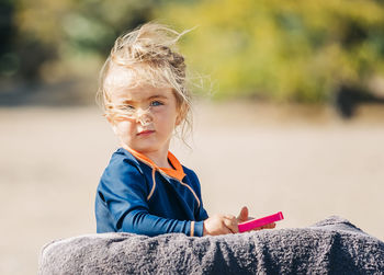 Portrait of cute girl standing by towel