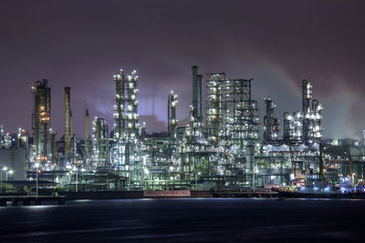 Illuminated factory against sky at night