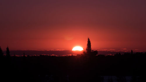 Silhouette trees on landscape against romantic sky at sunset