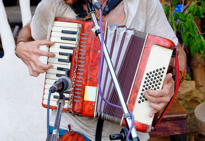 Midsection of man playing accordion outdoors