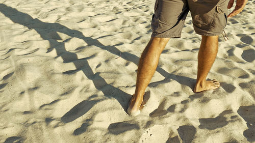 Low section of man standing on sand at beach