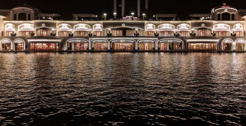 Illuminated building by river at night