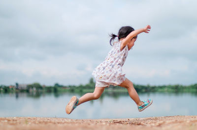 Girl running on field by river