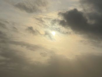 Low angle view of sunlight streaming through clouds