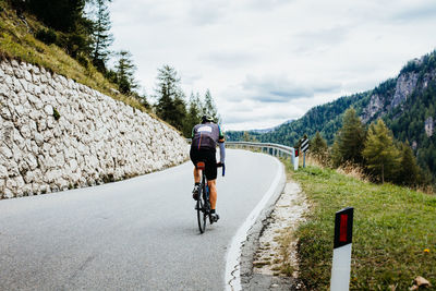 Rear view of man riding bicycle on road