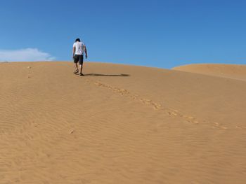 Rear view of man walking on sand at beach