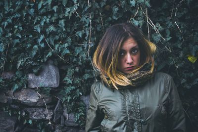 Portrait of beautiful young woman against trees