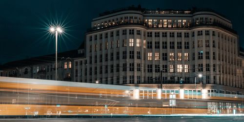 Light trails on street by buildings in city at night