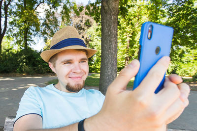 Portrait of smiling man holding mobile phone in park