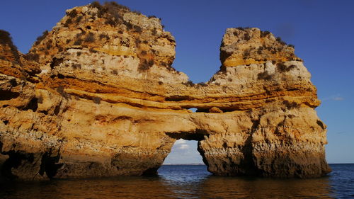 Rock formation in sea against clear sky
