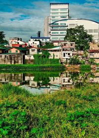 Buildings by lake against sky in city