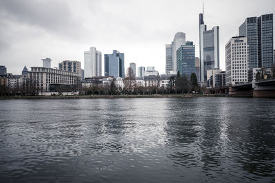 River by modern buildings in city against sky