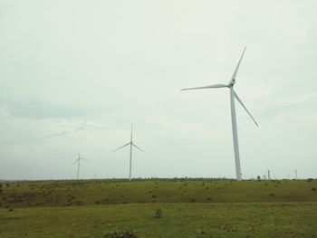 Windmills on field against sky